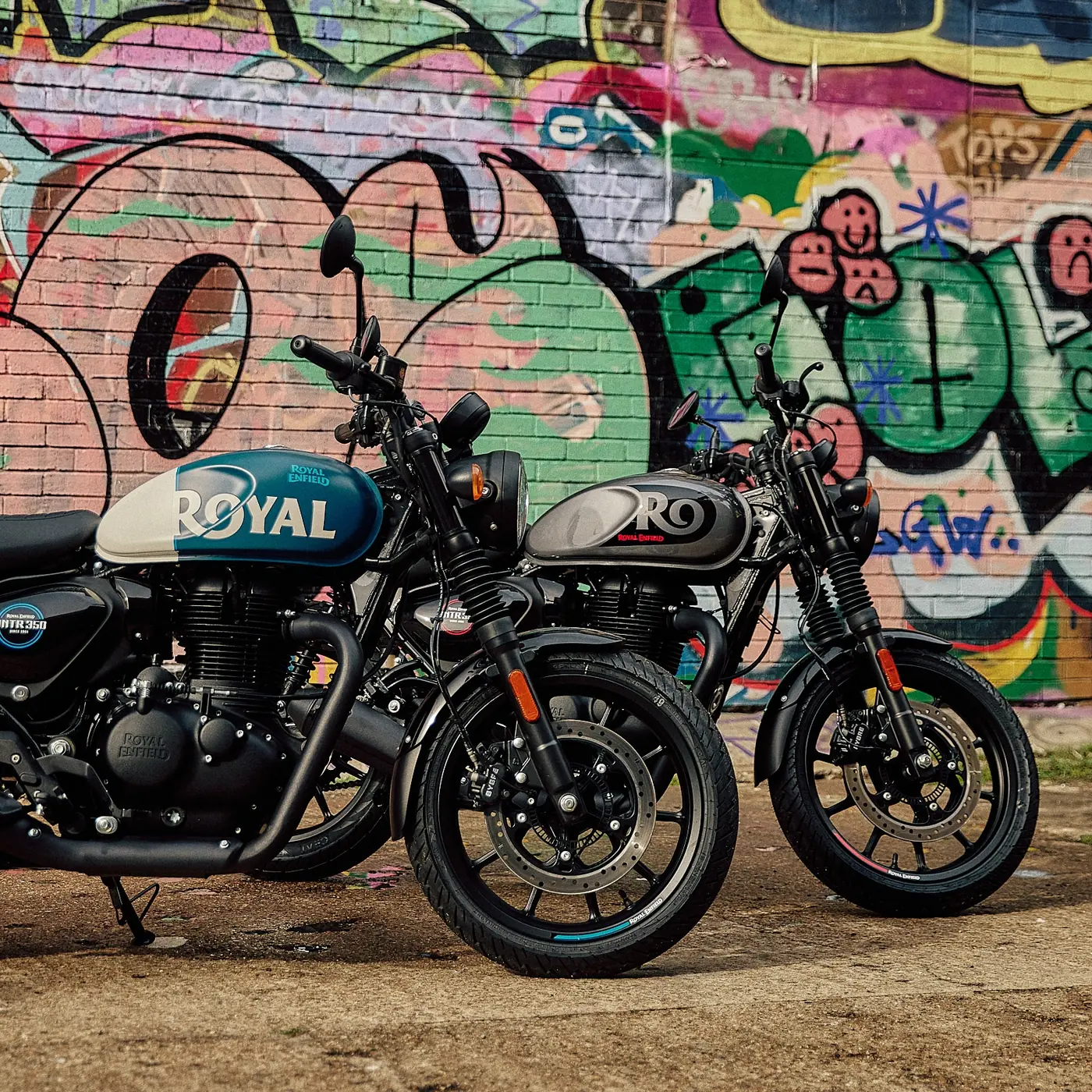Twee Royal Enfields voor een muur met graffiti