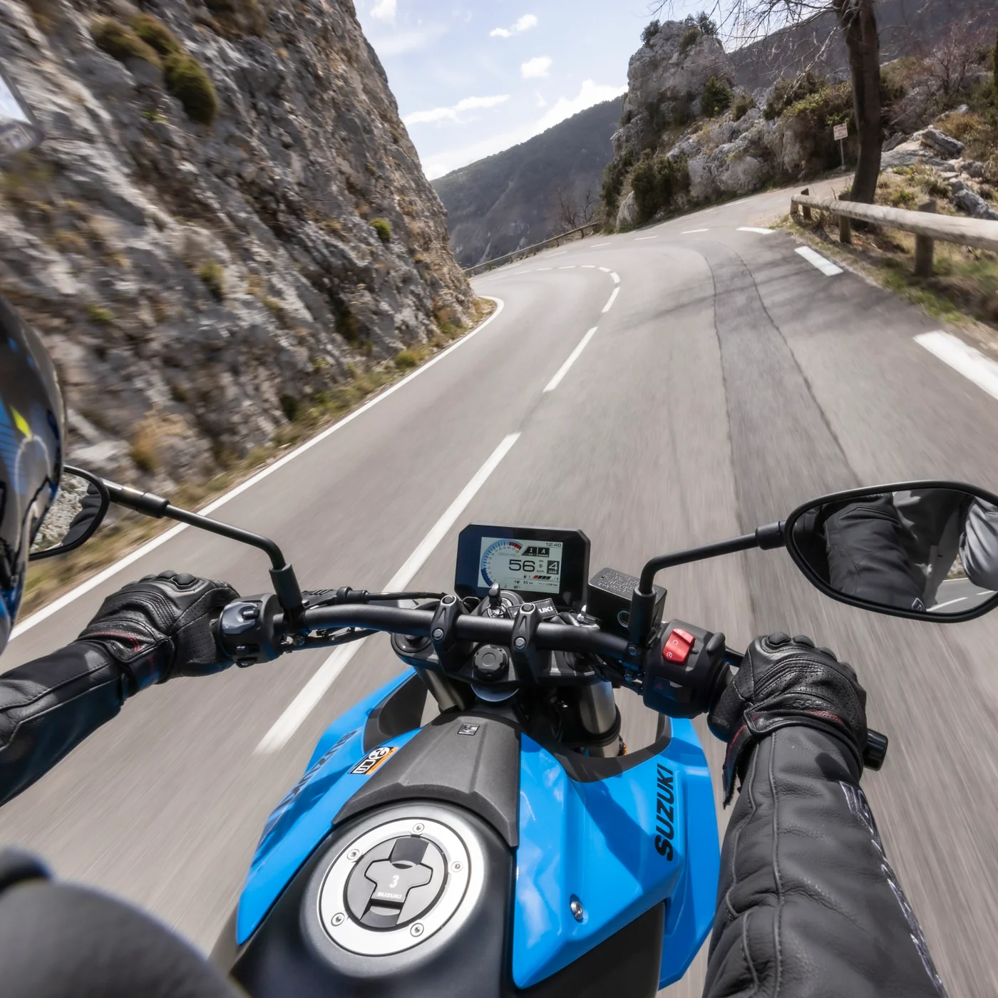 Blik over het stuur van een Suzuki op een bergweg